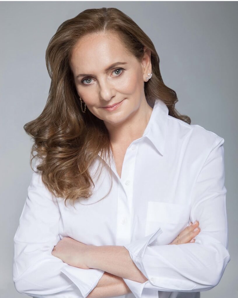 Professional woman in white shirt smiling with arms crossed